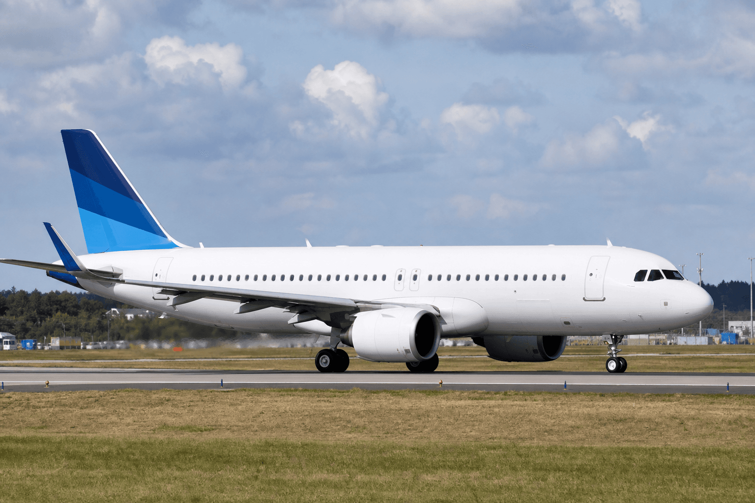 Airbus A320neo taxiing on runway at a major airport under clear skies