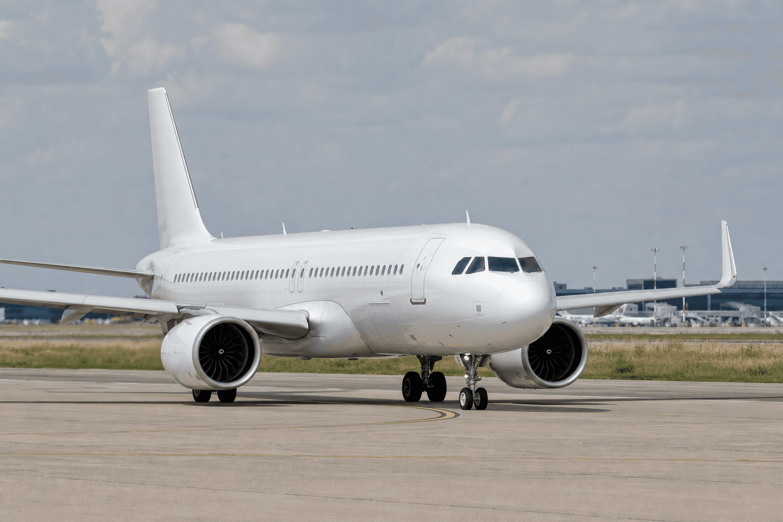 Airbus A320neo taxiing on runway with terminal background at daylight