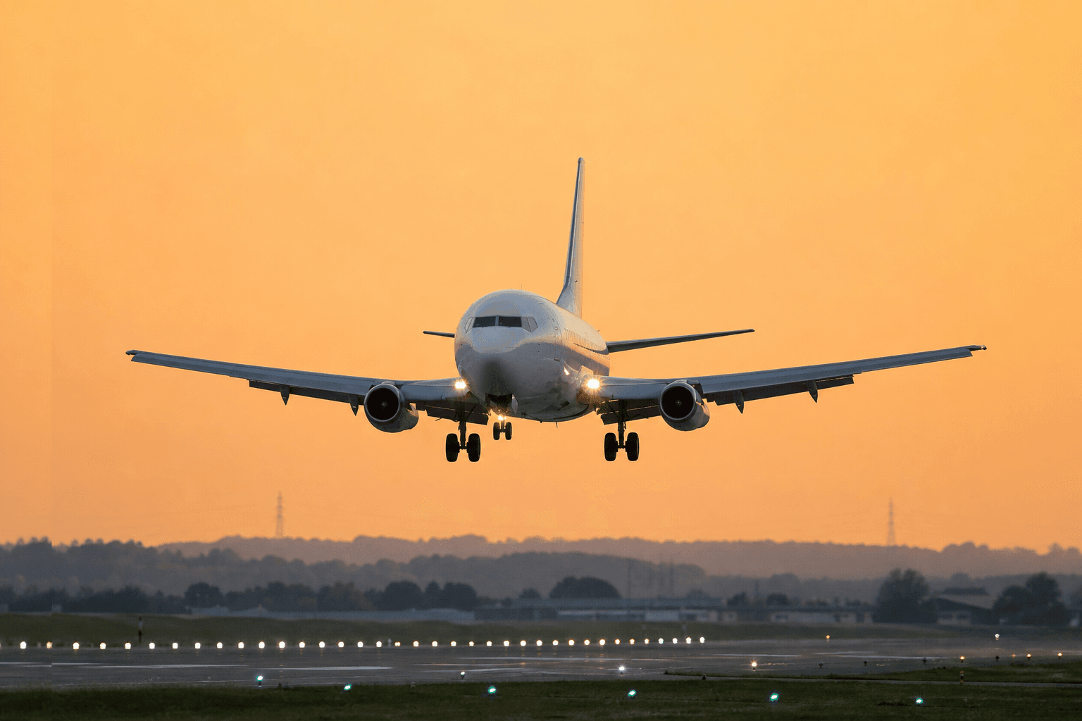 Boeing 737-200 aircraft in flight approaching an airport at dusk.