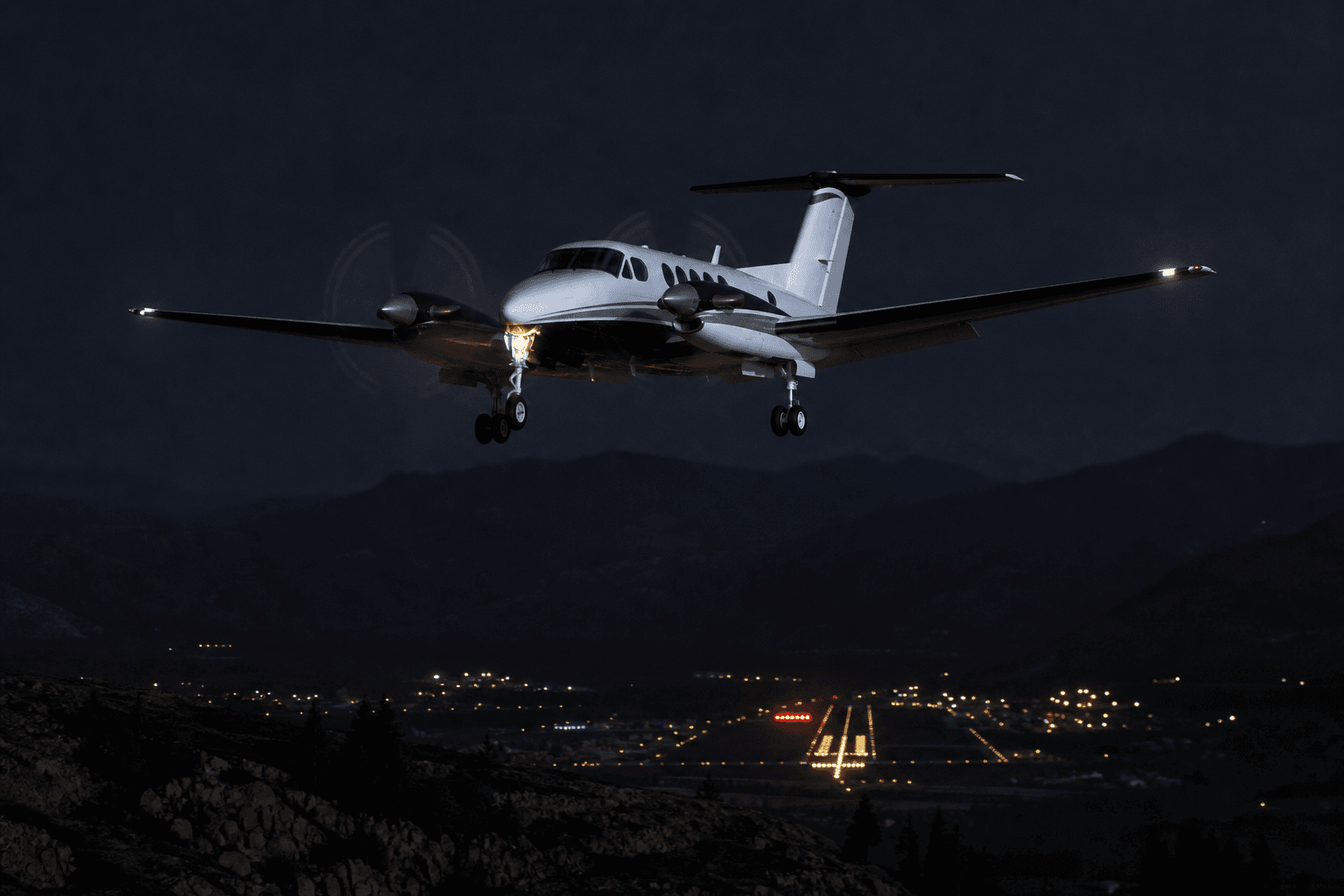 A Beechcraft King Air flying near mountainous terrain at night