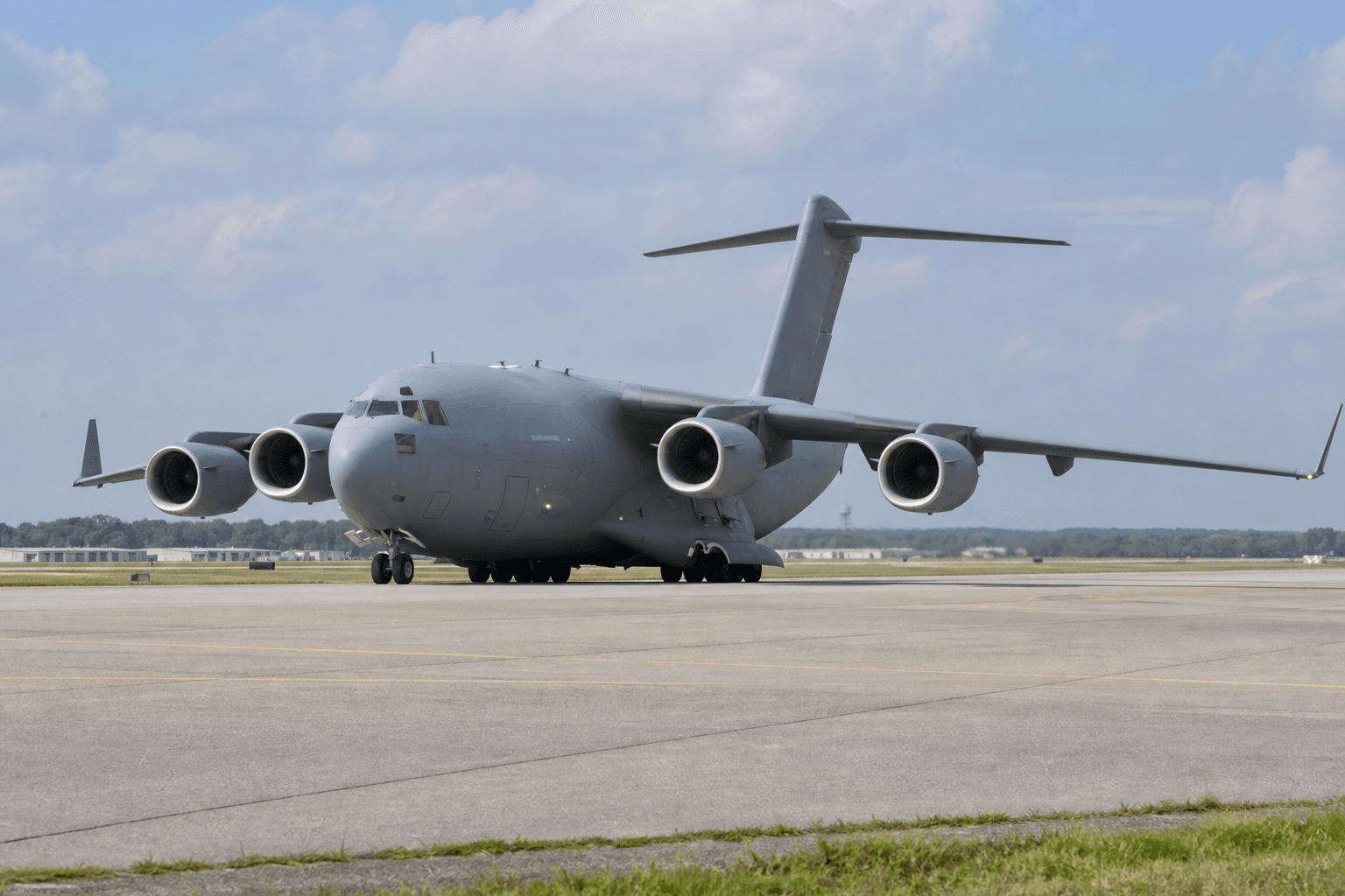 C-17 Globemaster III tactical airlifter taxiing at a military base runway under clear sky
