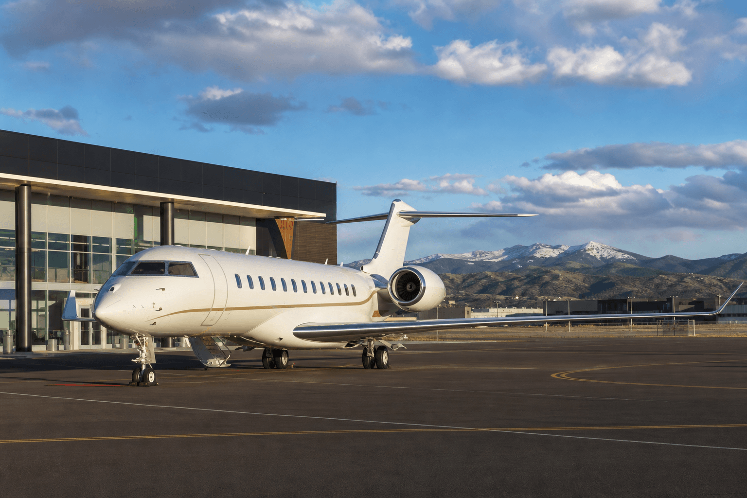 Business jet parked at a modern FBO facility at Rocky Mountain Metropolitan Airport under clear blue skies