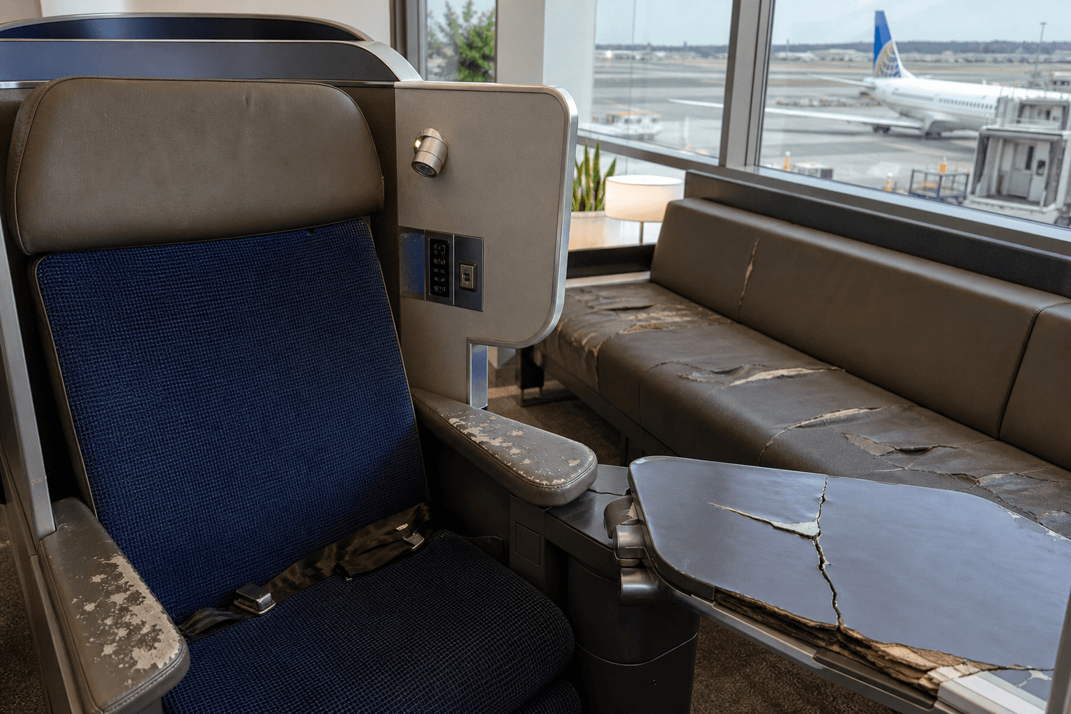 United Airlines passenger cabin showing worn premium seat and damaged lounge furniture