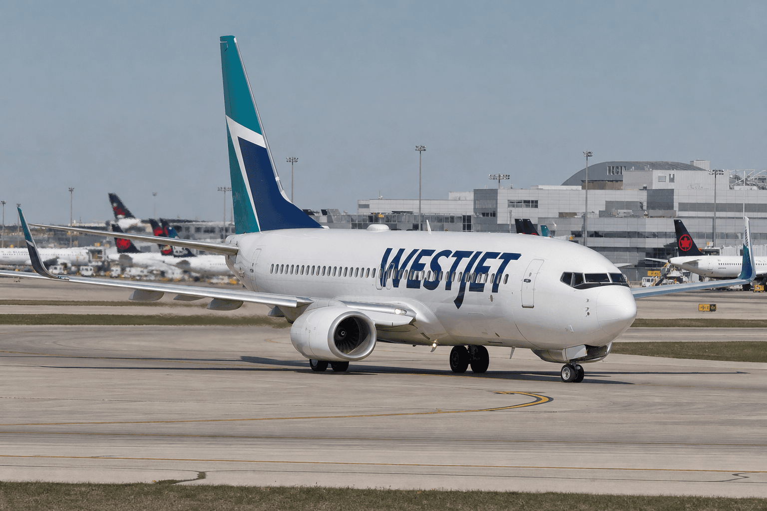 WestJet Boeing 737 on runway amid summer day with terminal in background