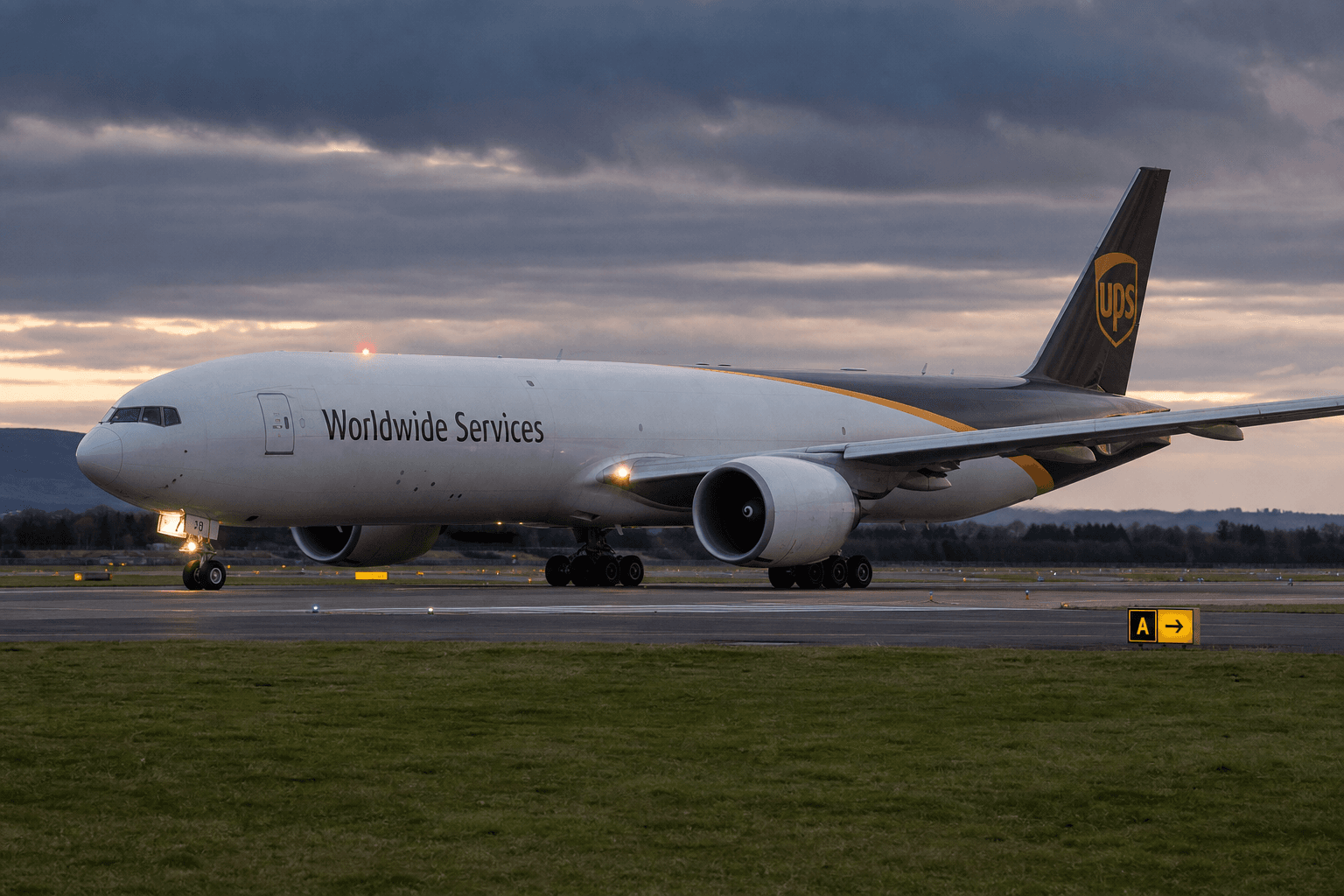 Boeing 777 freighter taxiing at a misty airport runway at night.
