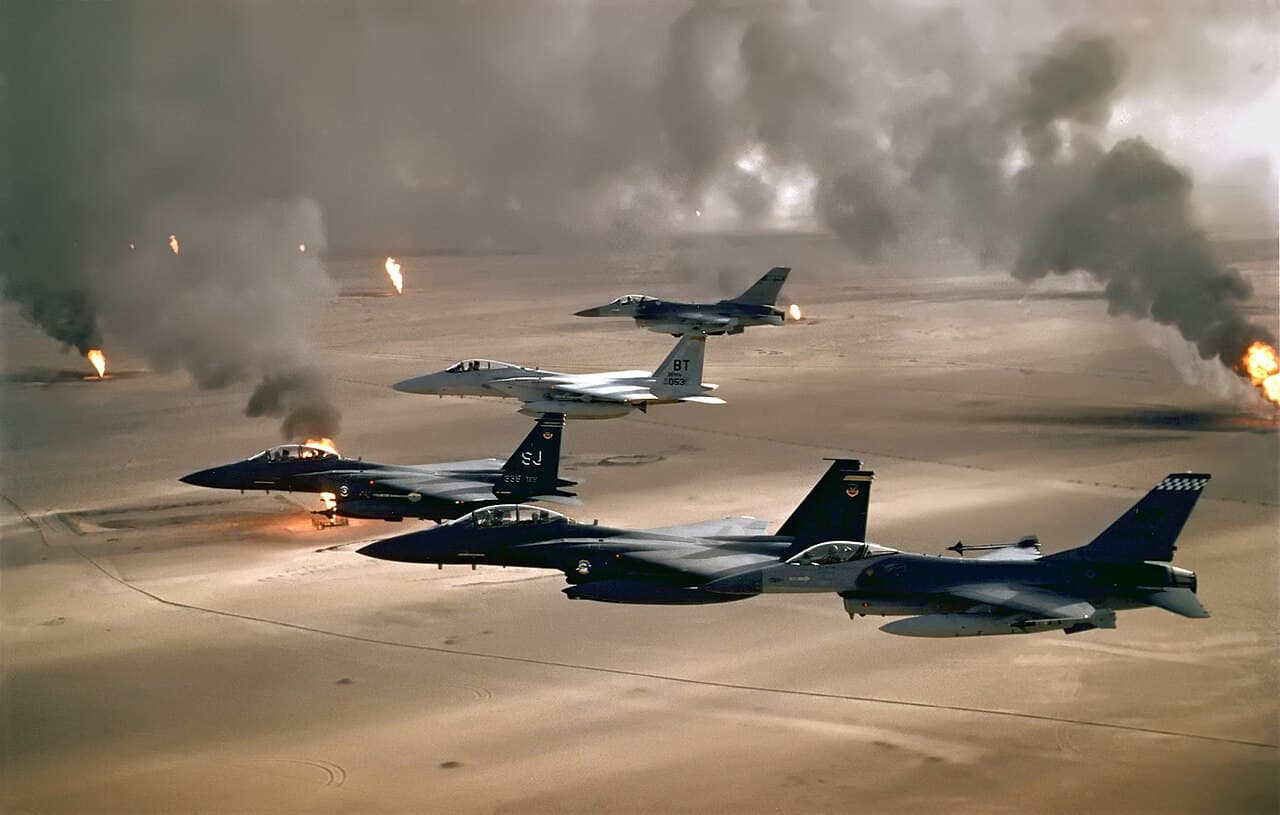 US Air Force Boeing F-15E Strike Eagle and KC-135 Stratotanker in midair refueling over desert terrain at dusk