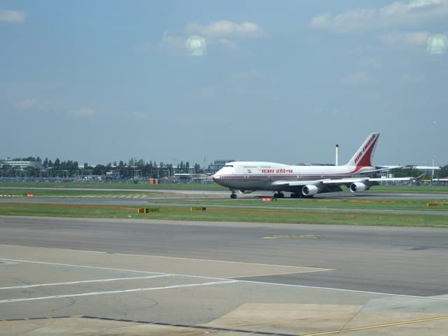 A large commercial aircraft taxiing on a runway at a major international airport in daylight.