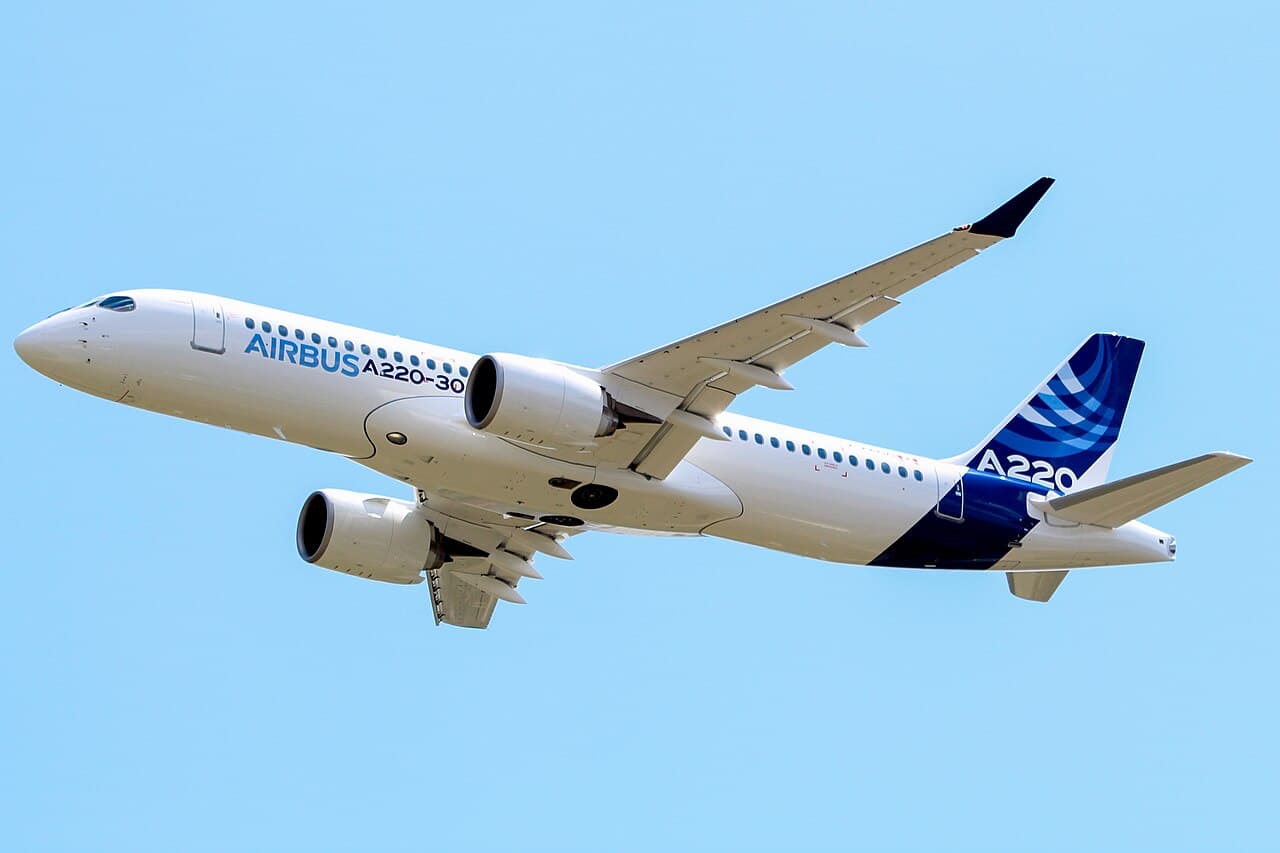 An airBaltic Airbus A220 taxiing at Riga International Airport on a clear day