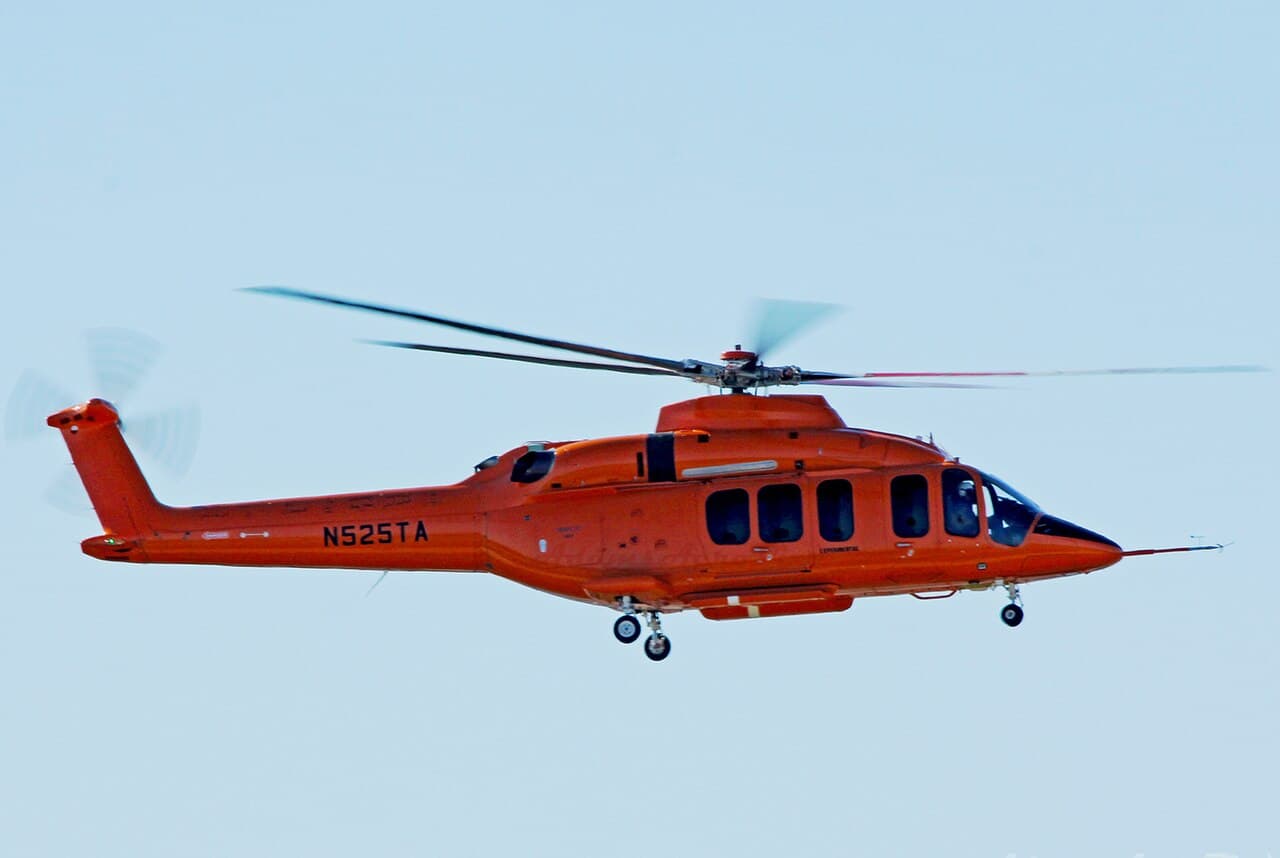 Bell 525 helicopter flying at low altitude over rugged terrain during daylight