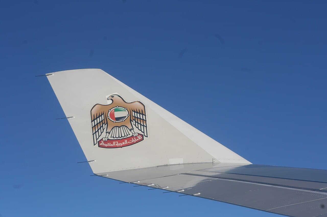 Etihad Airways aircraft taxiing with African airline logos in background at daytime airport