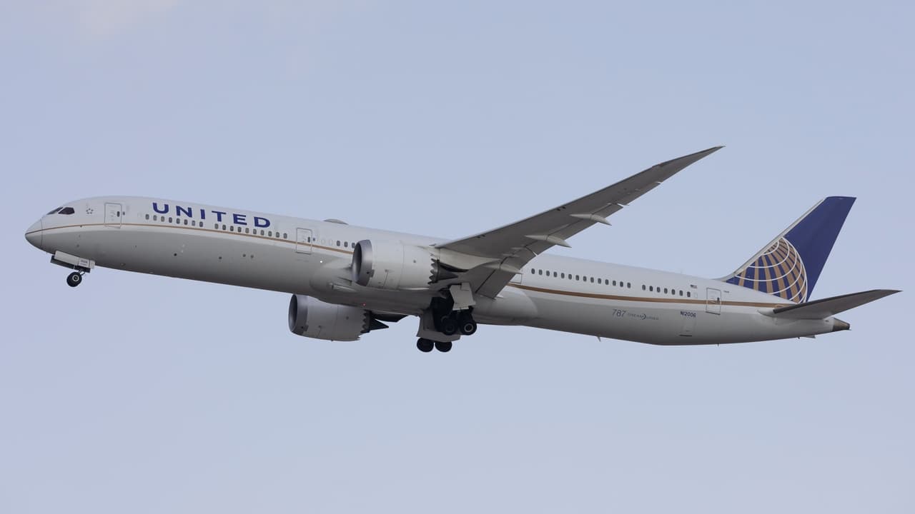 Boeing 767-300ER departing Newark Liberty International Airport with city skyline in background at sunset