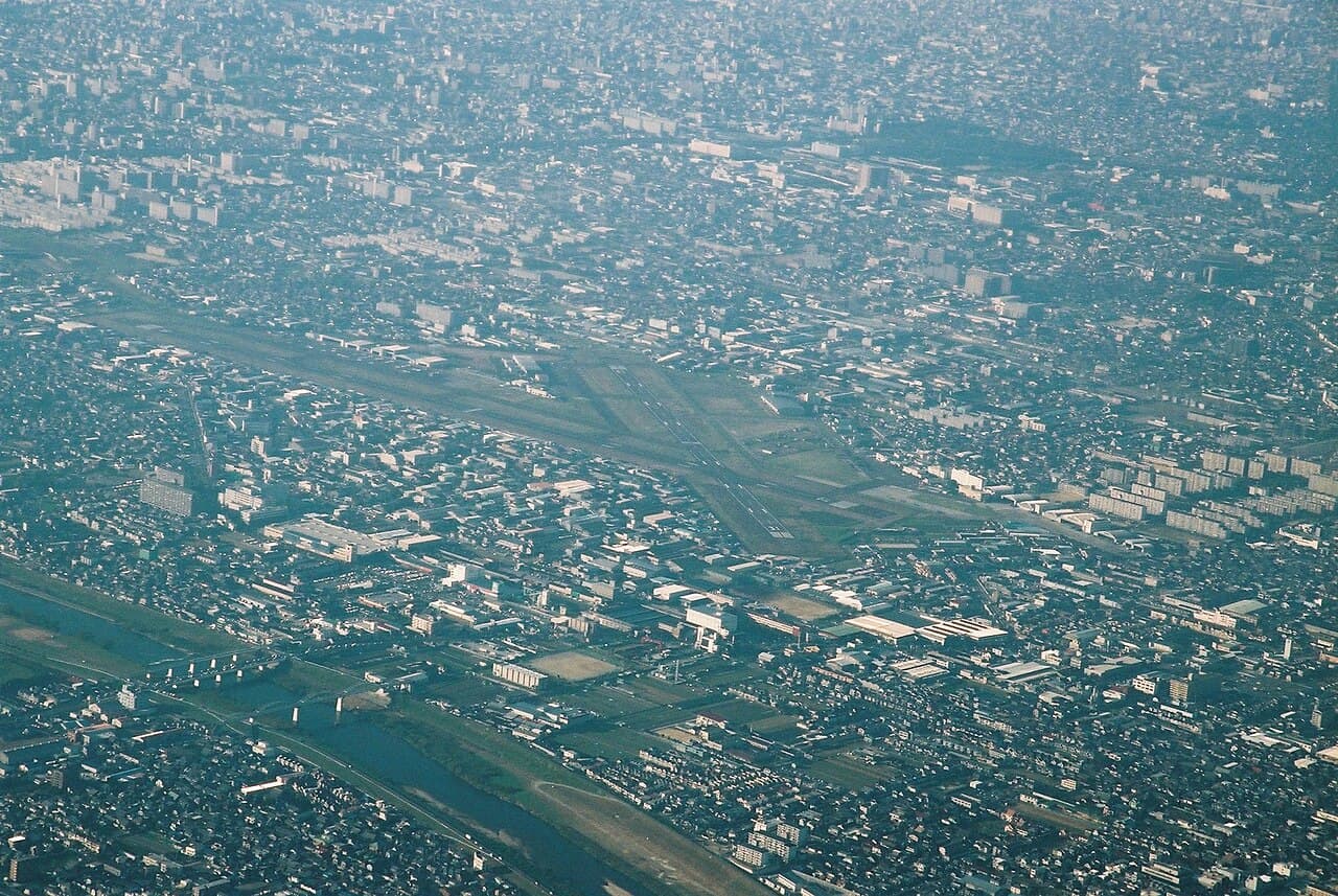 A HondaJet parked on a tarmac near a runway at a regional Japanese airport under overcast skies