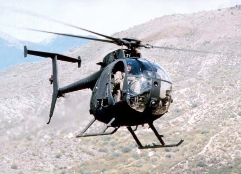 MH-6 Little Bird helicopter and MC-130J Commando II aircraft on desert airstrip