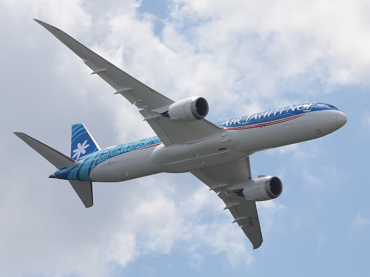 Boeing 787-9 taking off from a long runway at an international airport under cloudy sky