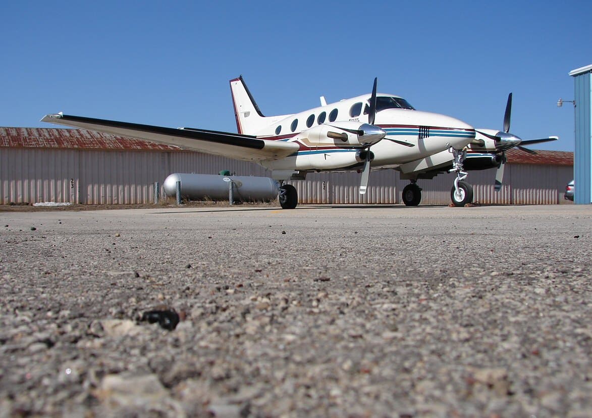 A Beechcraft King Air 90 flying near mountainous terrain during nighttime.