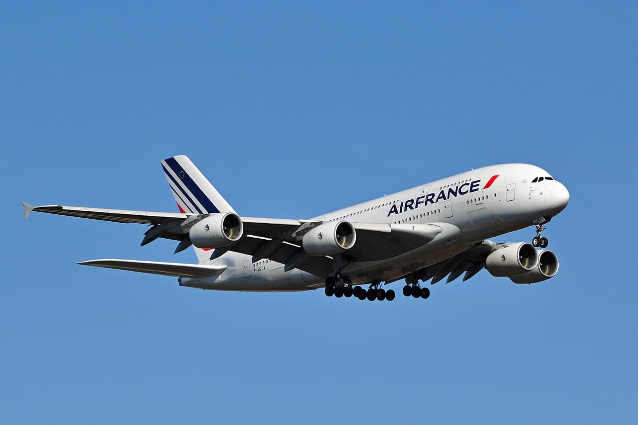A Boeing 777X with its folding wingtips deployed at an airport gate